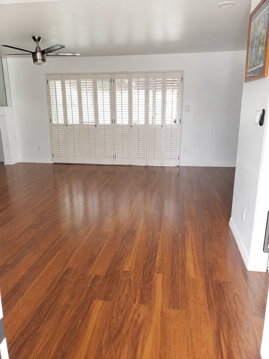Finished wood flooring in a bright living room with plantation shutter doors